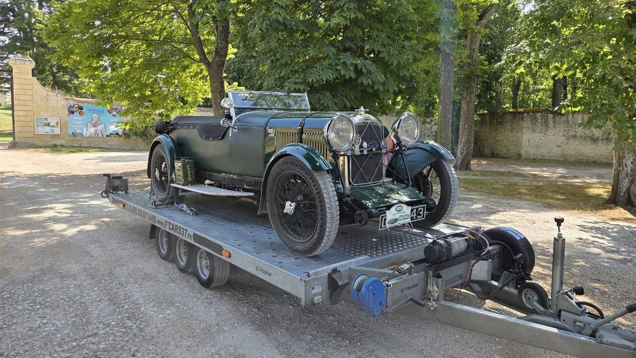 Automobile ancienne de rallye arrimée sur une remorque plateau dans l'allée d'un domaine